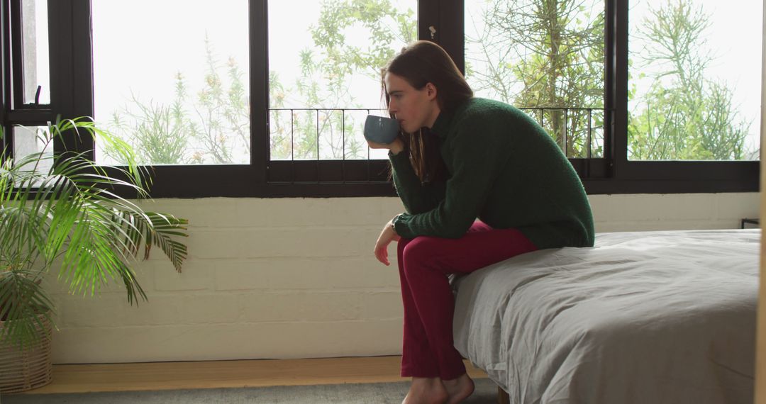 Thoughtful Woman Drinking Coffee in Modern Minimalistic Bedroom - Free Images, Stock Photos and Pictures on Pikwizard.com