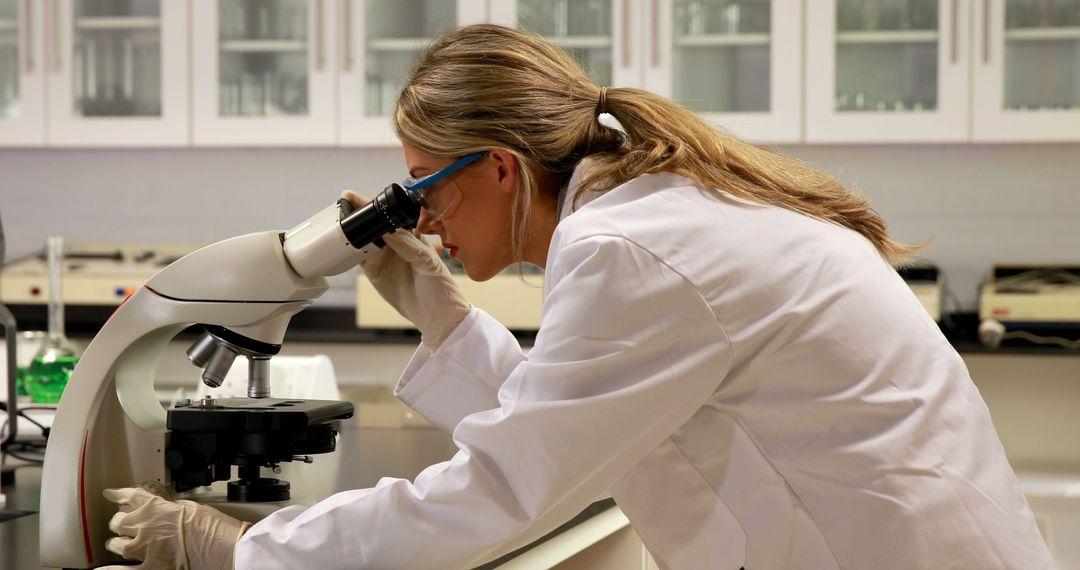 Female Scientist Examining Sample Through Microscope in Laboratory - Free Images, Stock Photos and Pictures on Pikwizard.com