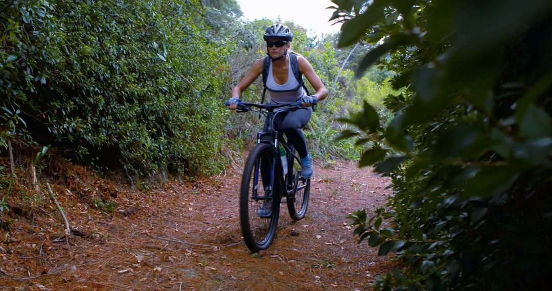 Woman mountain biking on forest trail in protective gear - Free Images, Stock Photos and Pictures on Pikwizard.com