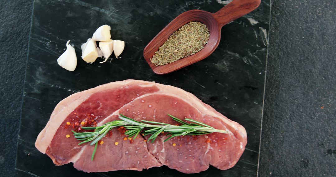 Raw Beef Steak with Rosemary and Garlic on Dark Background - Free Images, Stock Photos and Pictures on Pikwizard.com