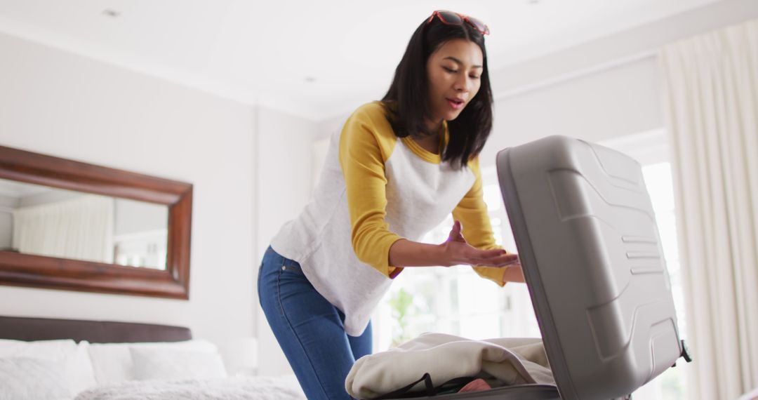 Image of biracial woman with dark hair packing suitcase - Free Images, Stock Photos and Pictures on Pikwizard.com