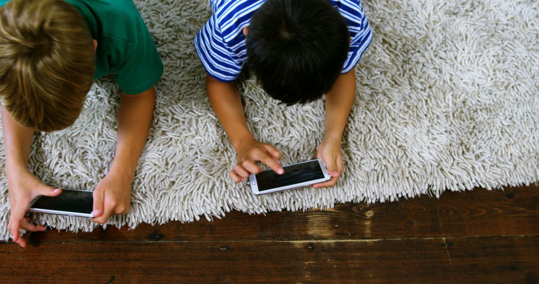 Children Lying on Rug Playing Games With Smartphones - Free Images, Stock Photos and Pictures on Pikwizard.com