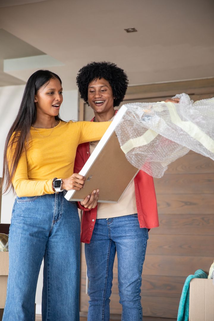 Diverse Couple Unpacking Picture Frame in New Home