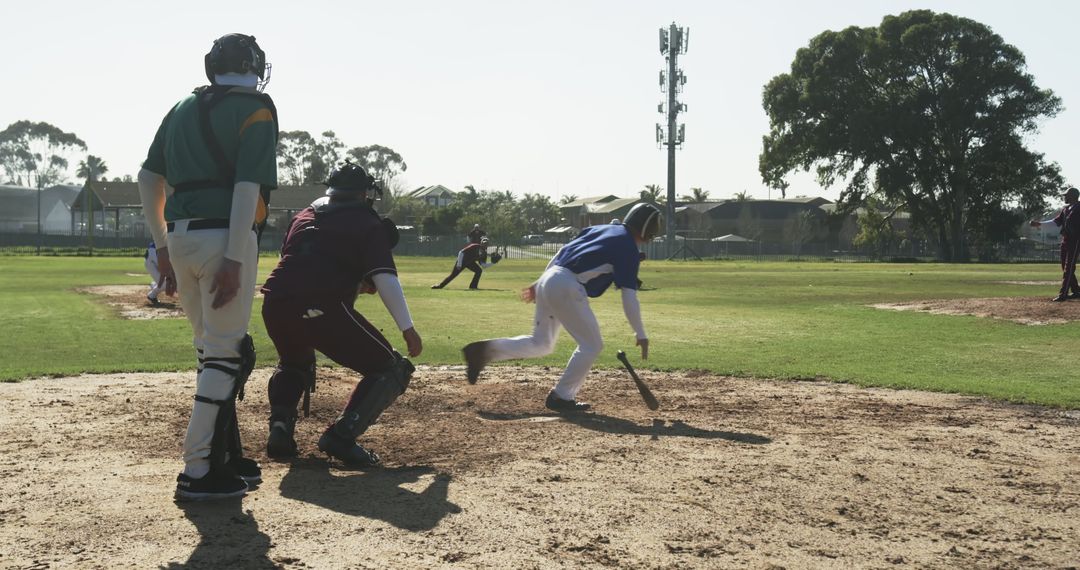 Youth Baseball Game Action with Batter Running to First Base