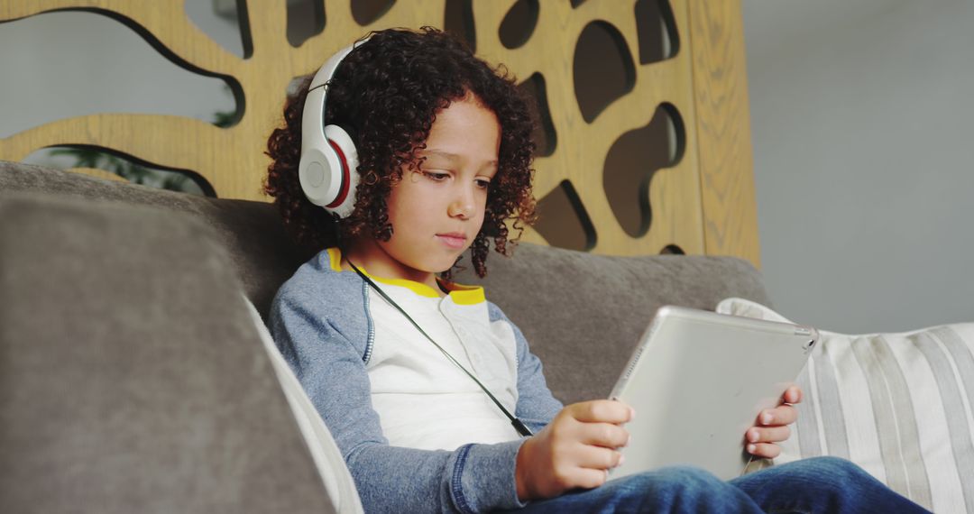 Child Using Tablet with Headphones on Sofa - Free Images, Stock Photos and Pictures on Pikwizard.com