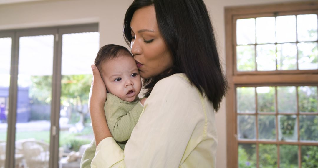Mother Gently Holding and Kissing Infant at Home