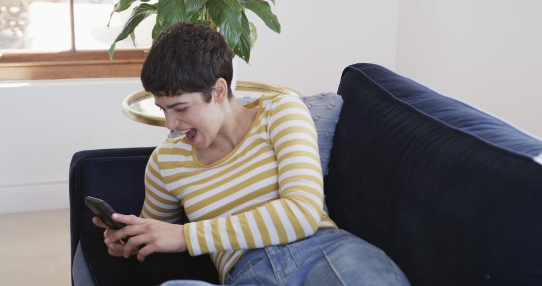 Laughing Woman Enjoying Smartphone on Cozy Sofa - Free Images, Stock Photos and Pictures on Pikwizard.com