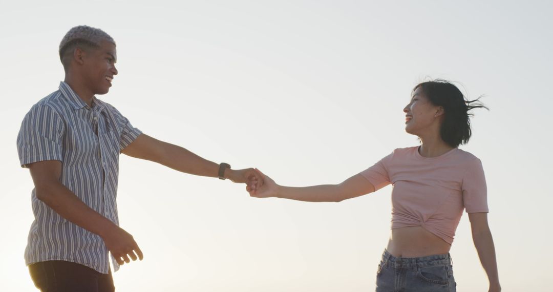 Interracial Couple Joyfully Dancing Outdoors During Sunset - Free Images, Stock Photos and Pictures on Pikwizard.com