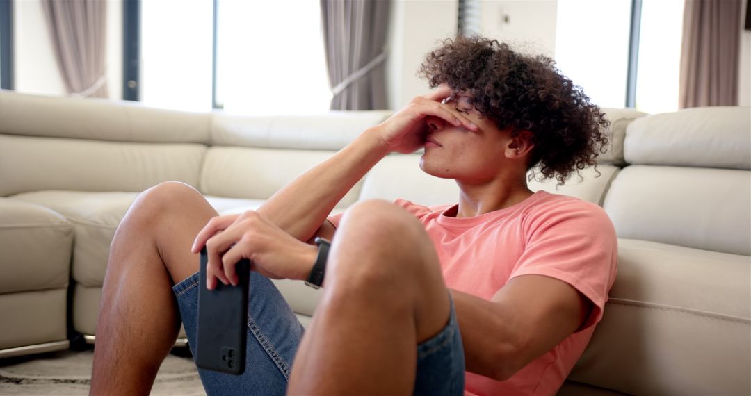 Upset Young Man with Smartphone in Contemplative Mood