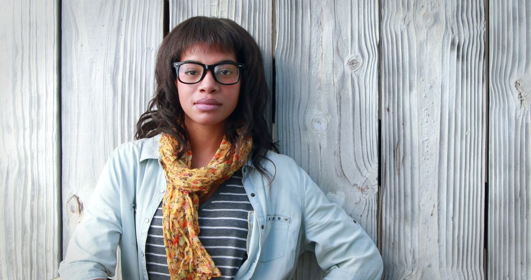 Confident Woman with Glasses Leaning Against Wooden Wall Wearing Scarf - Free Images, Stock Photos and Pictures on Pikwizard.com