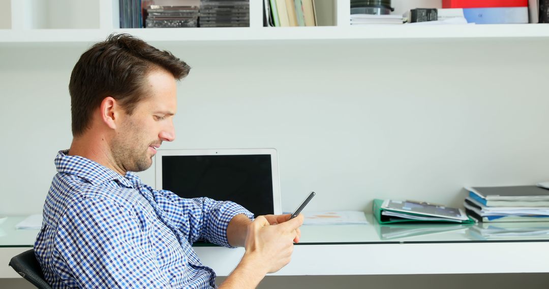 Man Sitting in Home Office Checking Smartphone - Free Images, Stock Photos and Pictures on Pikwizard.com