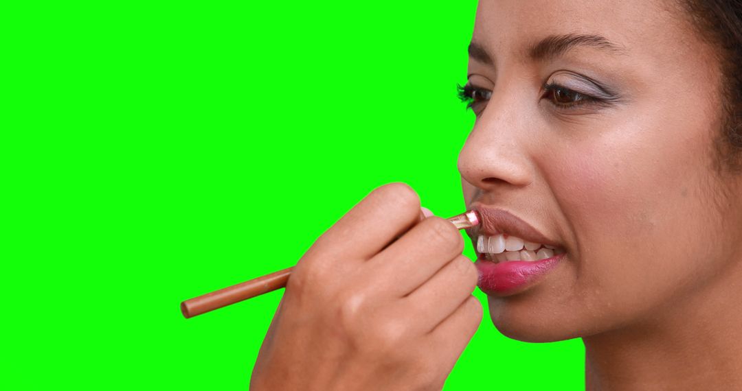 African American Woman Applying Lip Pencil on Green Background - Free Images, Stock Photos and Pictures on Pikwizard.com