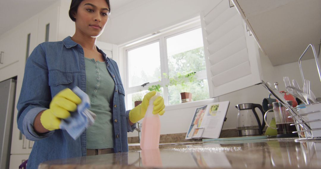 Image of happy biracial woman cleaning kitchen - Free Images, Stock Photos and Pictures on Pikwizard.com