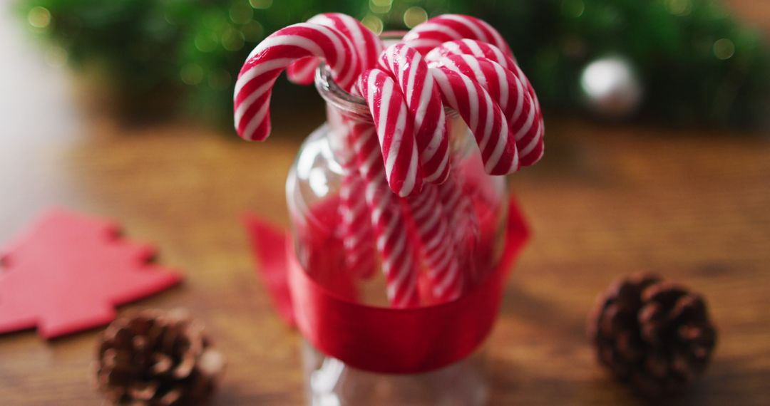 Candy Canes in Glass Jar with Red Ribbon and Pine Cones on Wooden Table - Free Images, Stock Photos and Pictures on Pikwizard.com