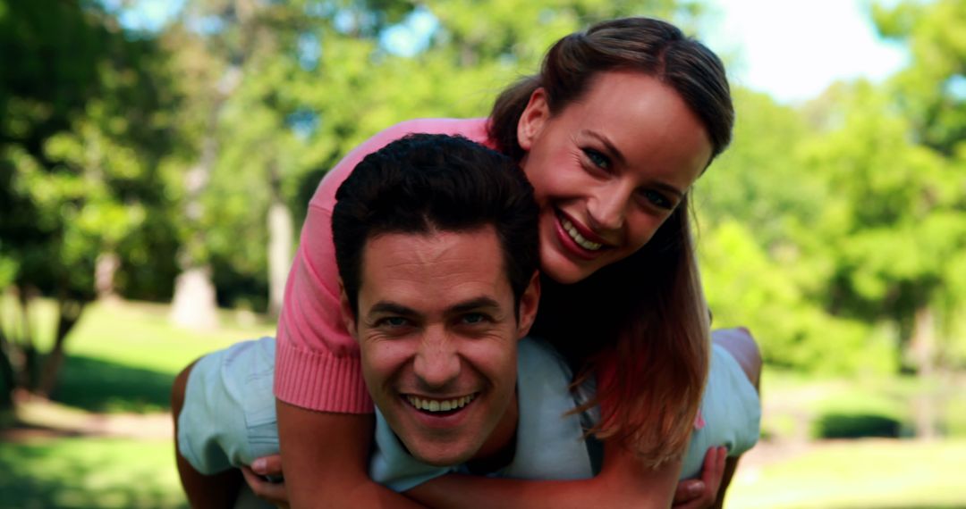 Couple Enjoying Piggyback Ride on Sunny Day in Park