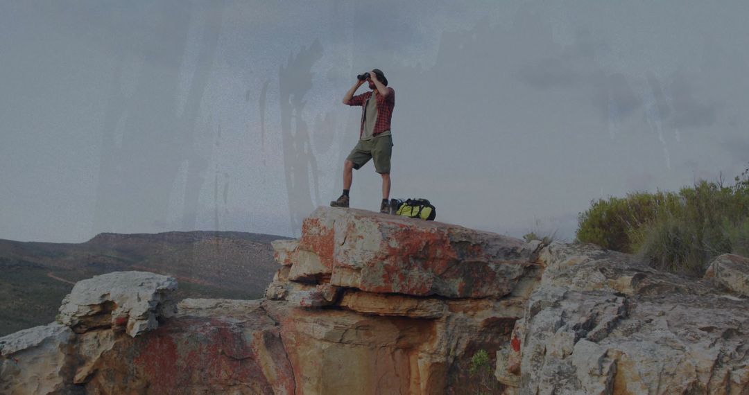 Hiker Observing Majestic Canyon Views with Binoculars on Rocky Ledge
