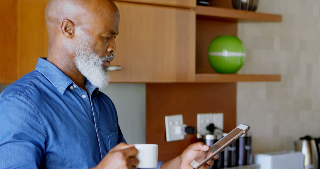 Senior African American Man Reading Digital Tablet in Kitchen - Free Images, Stock Photos and Pictures on Pikwizard.com