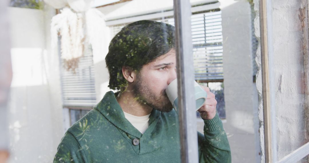 Man Drinking Coffee by Window Reflecting Outdoor Scenery - Free Images, Stock Photos and Pictures on Pikwizard.com