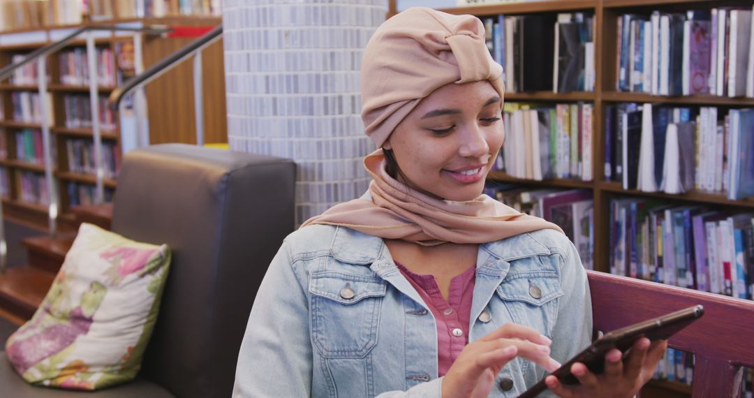 Woman in Headscarf Using Tablet in Library with Happy Expression - Free Images, Stock Photos and Pictures on Pikwizard.com