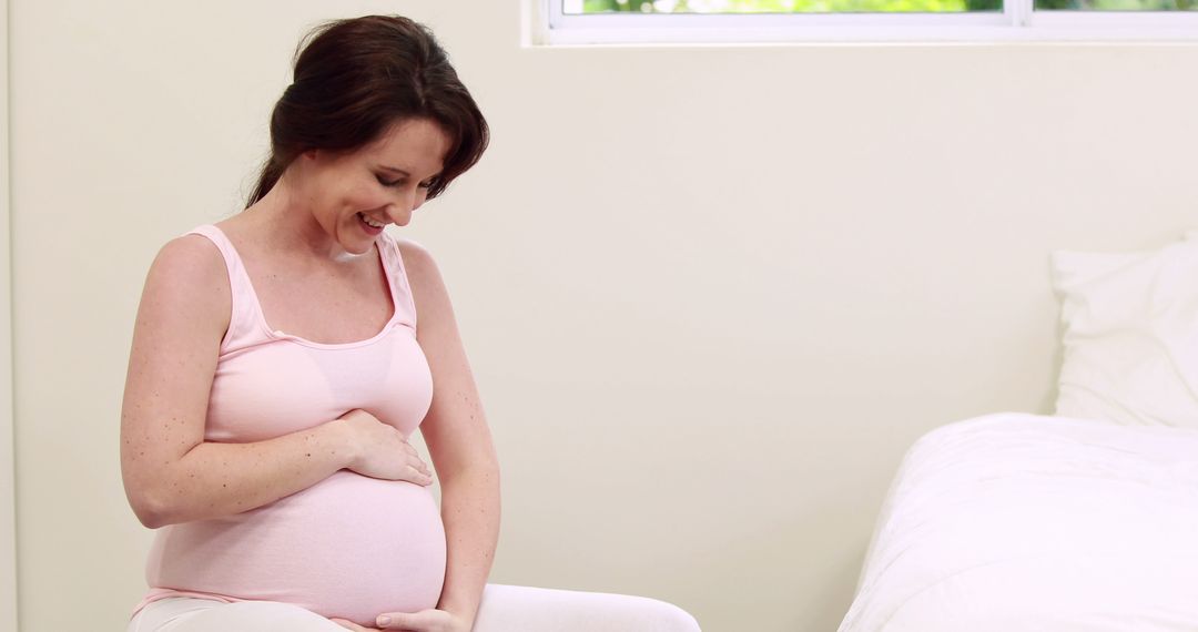 Pregnant Woman Smiling and Holding Belly in Bedroom - Free Images, Stock Photos and Pictures on Pikwizard.com