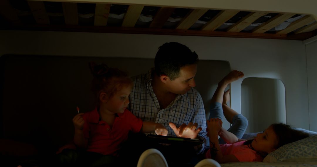 Father Reading Story on Tablet to Toddlers in Low Light - Free Images, Stock Photos and Pictures on Pikwizard.com