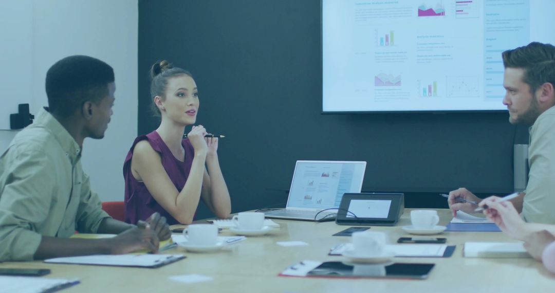 Woman presenting data in modern boardroom meeting with laptop and analytics display