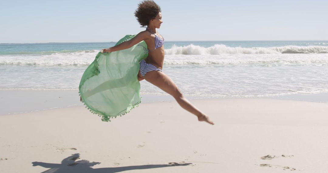 Woman Jumping in Excitement on Beach Wearing Green Wrap and White Bikini - Free Images, Stock Photos and Pictures on Pikwizard.com