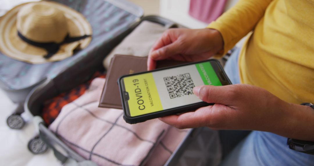 Packing for Travel Holding COVID-19 Passport on Smartphone