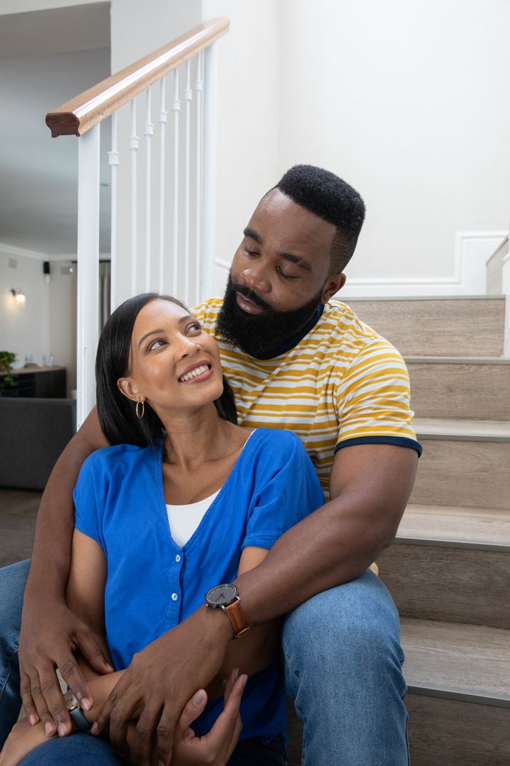 Diverse Couple Embracing on Wooden Staircase Displaying Love and Elegance