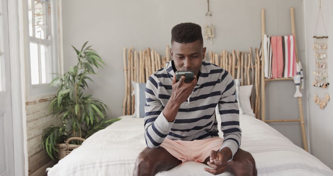 Man Using Smartphone Voice Command in Cozy Bedroom - Free Images, Stock Photos and Pictures on Pikwizard.com