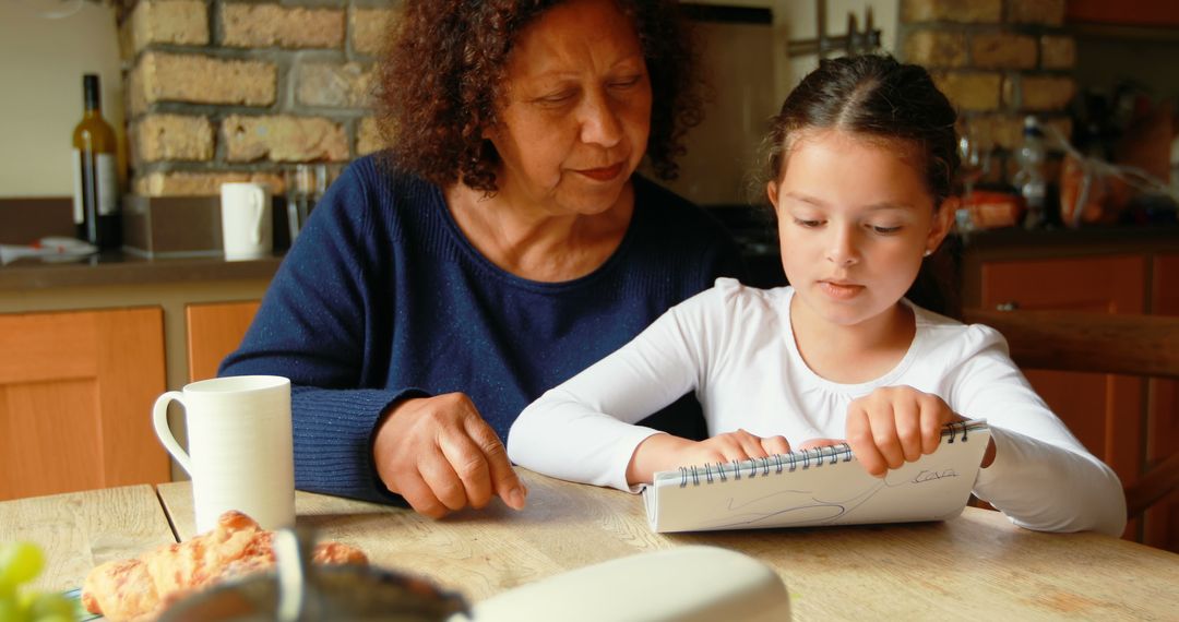 Grandmother Helping Granddaughter with Homework in Kitchen - Free Images, Stock Photos and Pictures on Pikwizard.com