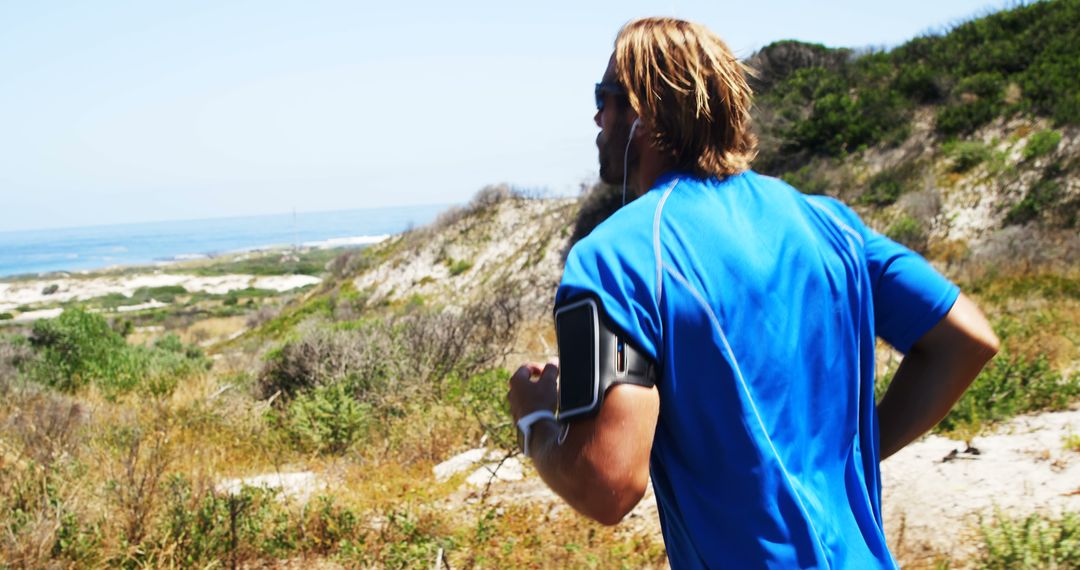 Man Running on Trail Near Beach with Earphones - Free Images, Stock Photos and Pictures on Pikwizard.com