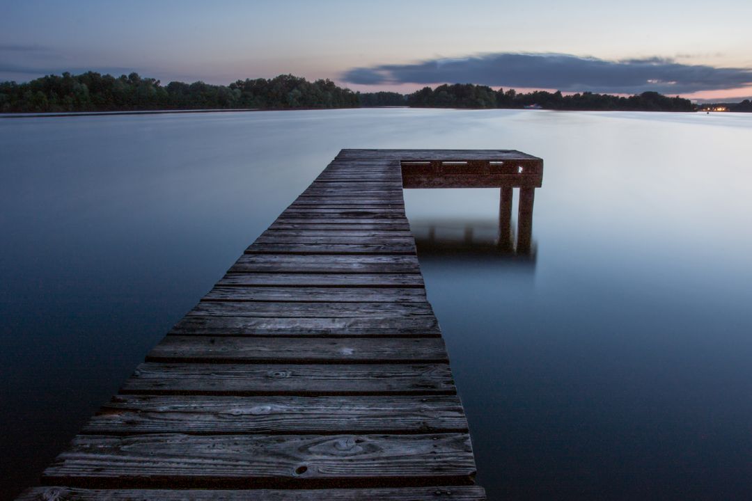 Serene Wooden Dock Stretching Out over Calm Waters at Twilight - Free Images, Stock Photos and Pictures on Pikwizard.com