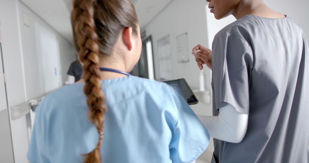 Diverse Female Doctors Collaborating Using Tablet in Hospital Corridor - Free Images, Stock Photos and Pictures on Pikwizard.com