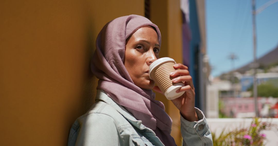 Woman in Hijab Enjoying Coffee Outdoors on a Sunny Day - Free Images, Stock Photos and Pictures on Pikwizard.com