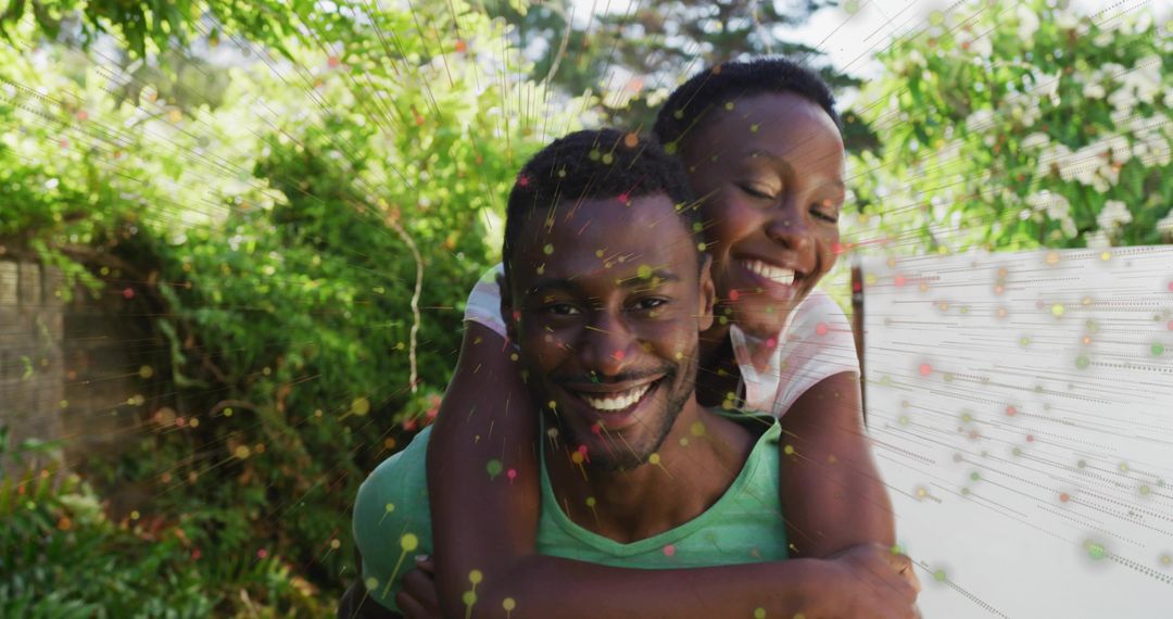 Couple sharing piggyback laughter in sunlit backyard with vibrant particle overlay