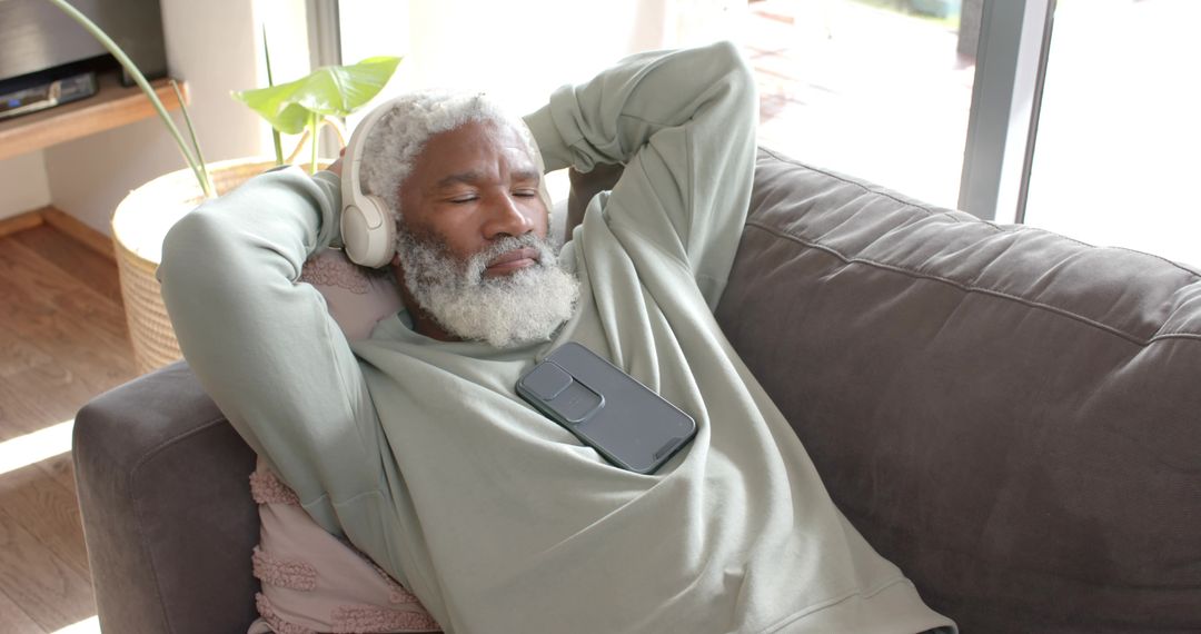 Senior Man Relaxing at Home with Headphones and Smartphone