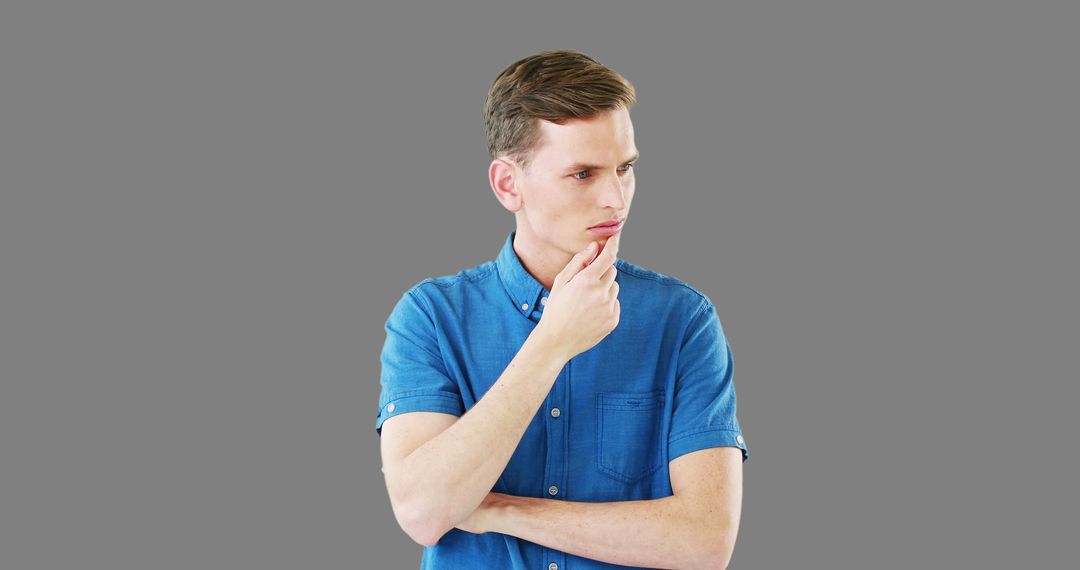 Thinking Young Man in blue shirt isolated on gray background - Free Images, Stock Photos and Pictures on Pikwizard.com
