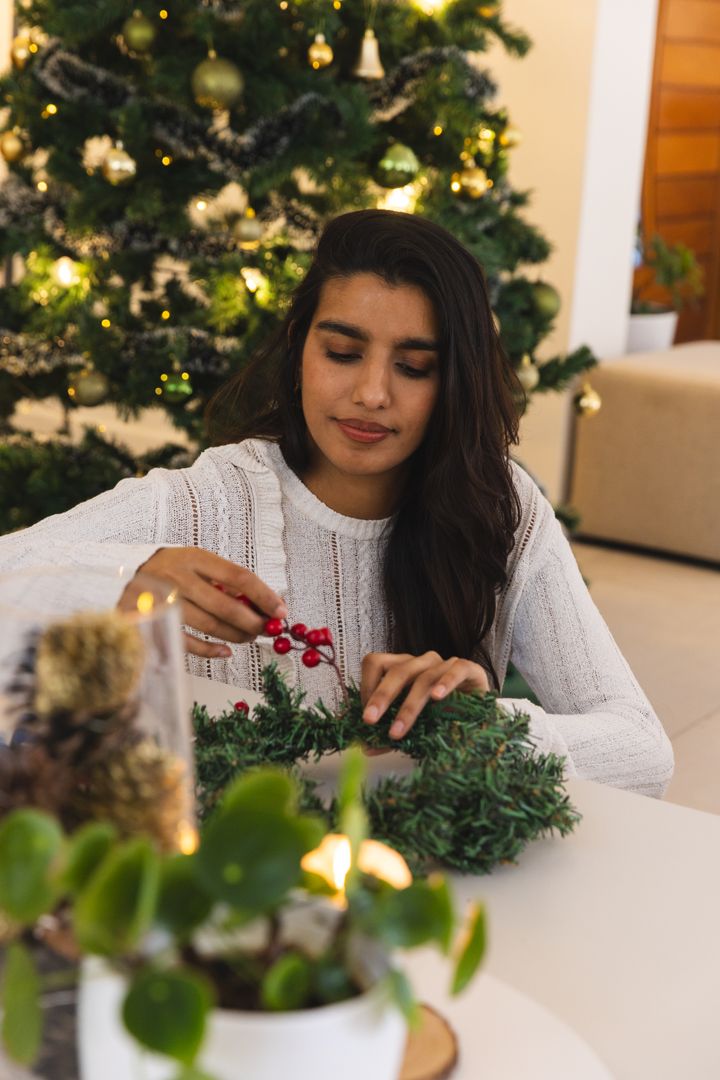 Indian Woman Creating Festive Wreath Near Christmas Tree
