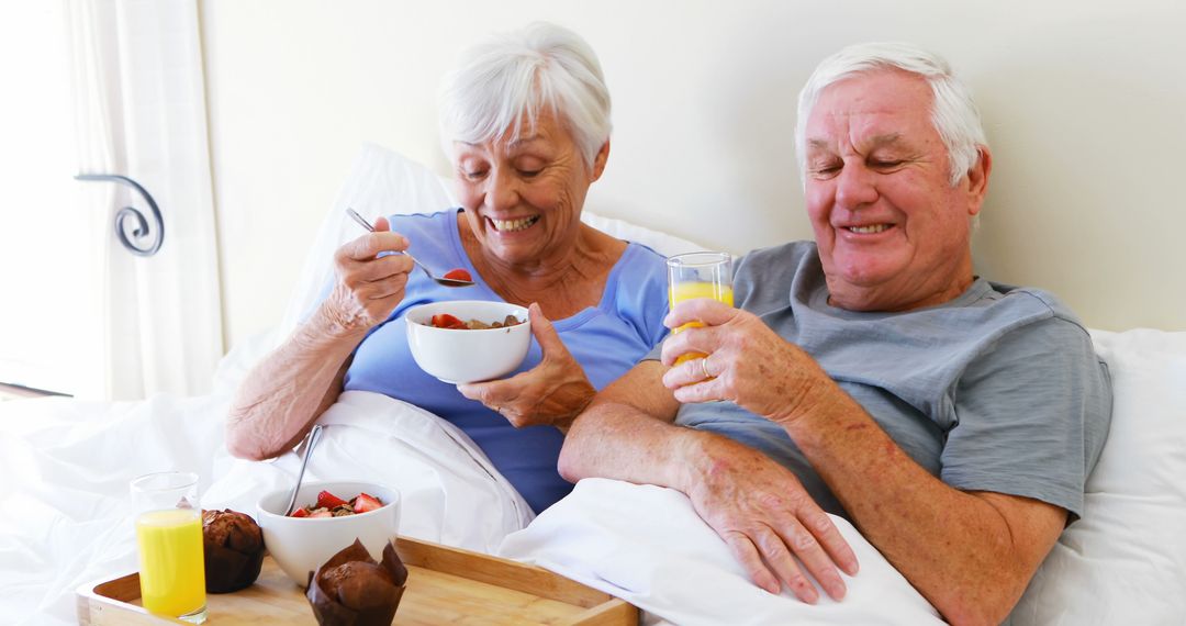 Senior Couple Enjoying Breakfast in Bed with Laughter