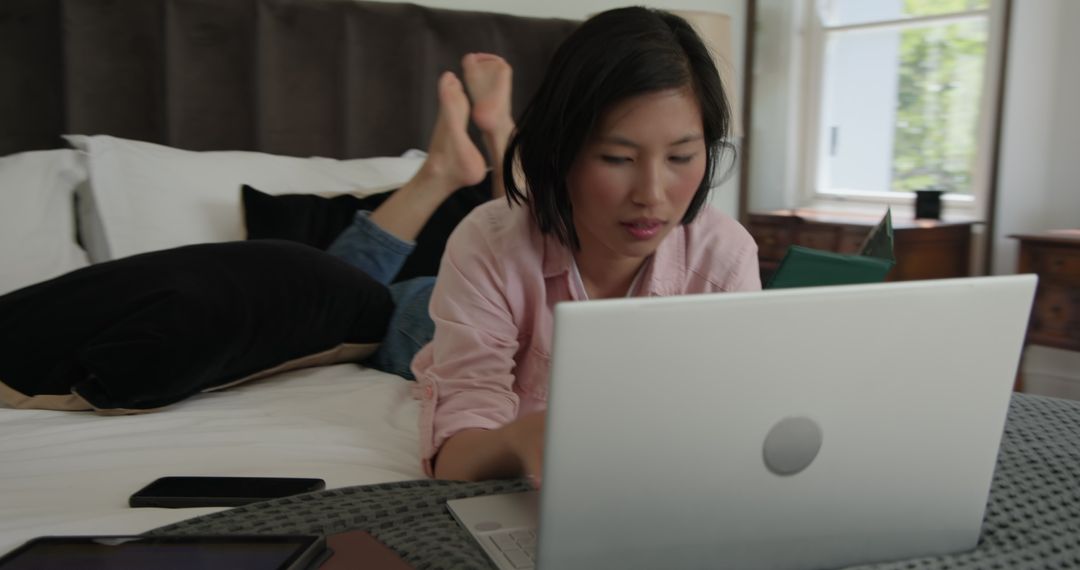 Asian Woman Online Shopping on Laptop in Cozy Bedroom