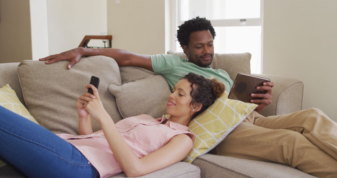 Multiracial Couple Relaxing with Technology on Cozy Sofa