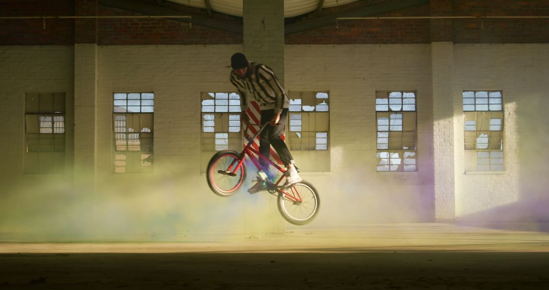 BMX Rider Performing Stunt in Abandoned Warehouse with Colored Smoke - Free Images, Stock Photos and Pictures on Pikwizard.com