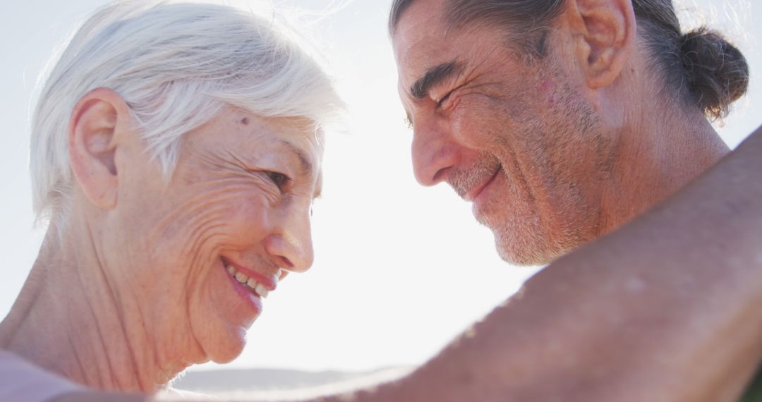 Elderly Couple Embracing and Smiling on Sunny Beach Day