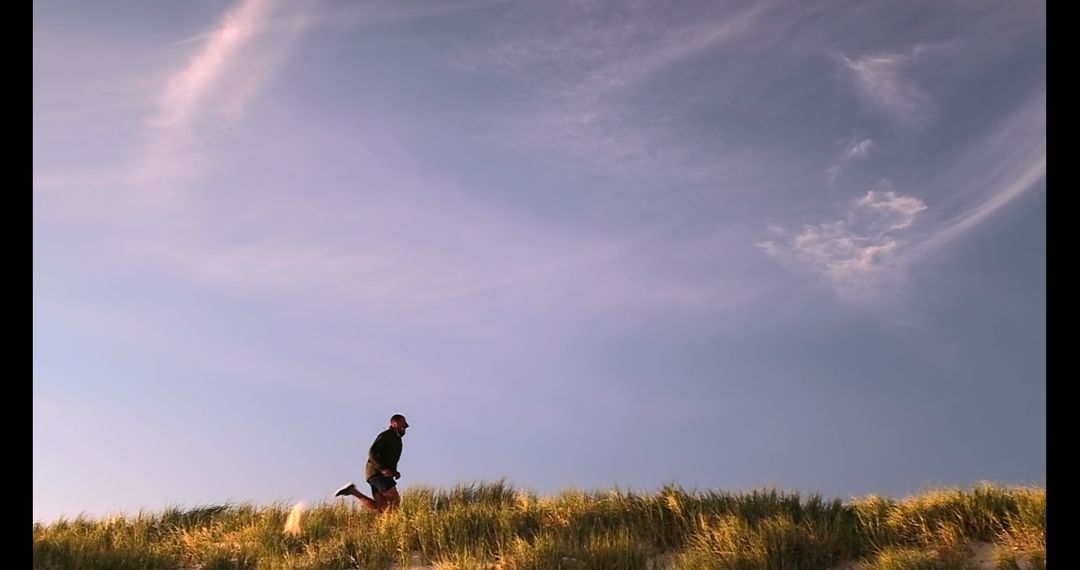 Young Runner Jogging on Sandy Dunes Against Scenic Sky