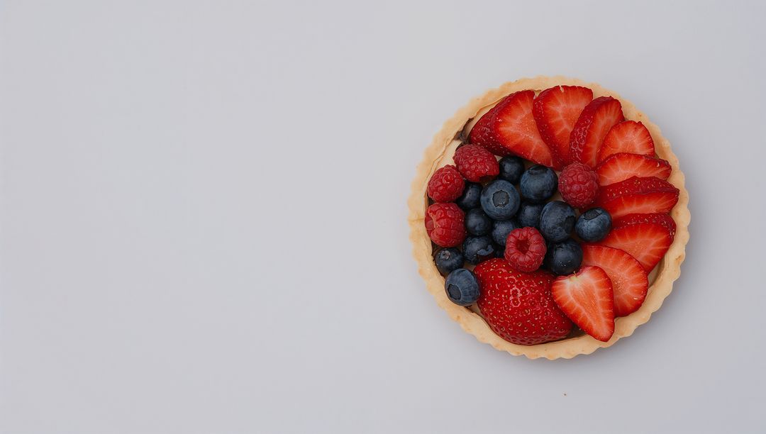 Displaying mixed berry tart on white tabletop with fluted crust overhead and copy space