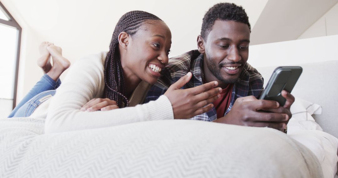 Couple Relaxing on Bed with Smartphone in Bright Bedroom
