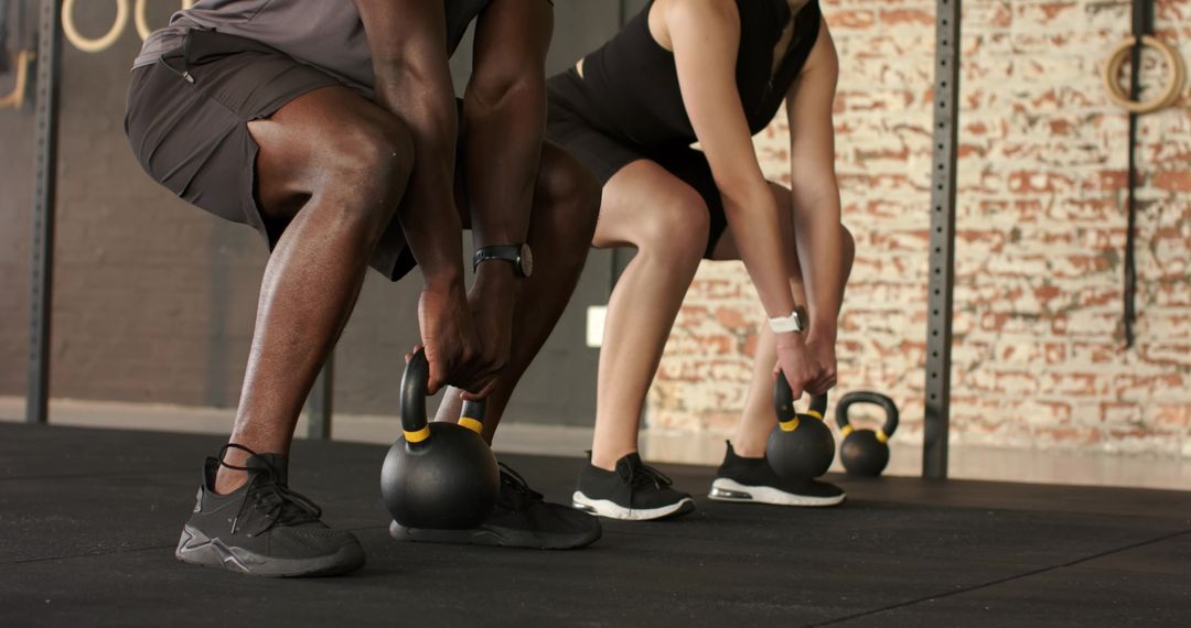 Diverse Athletes Exercising with Kettlebells in Modern Gym