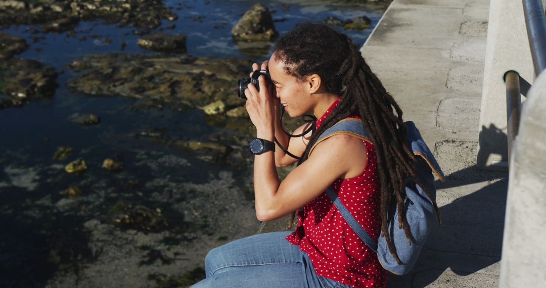 Woman with Long Dreadlocks Photographing Ocean from Stone Pier - Free Images, Stock Photos and Pictures on Pikwizard.com