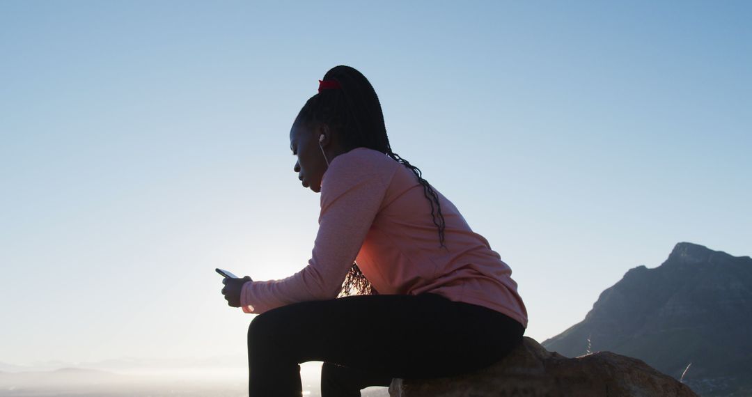 Woman Sitting Outdoors Texting On Smartphone With Mountain Background - Free Images, Stock Photos and Pictures on Pikwizard.com